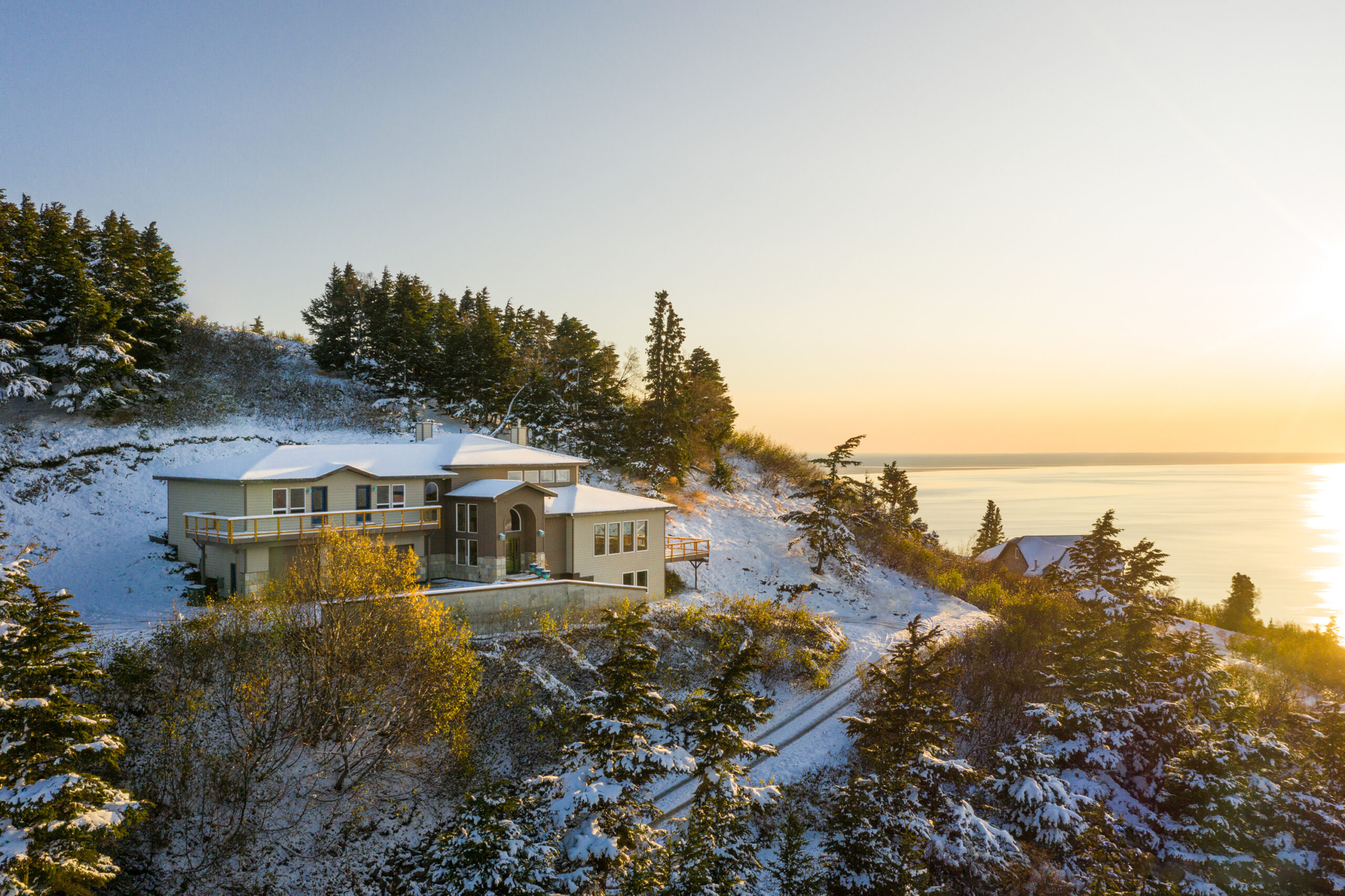 Captured by the talented Marcus Biastock, this image from Anchorage, Alaska, is a testament to the serene beauty of winter. The photograph reveals a cozy abode, its windows aglow with the golden light of dawn, reflecting the promise of a new day. Surrounded by snow-draped pines and overlooking the still waters that mirror the sky’s blush, this scene is a romantic haven where moments are cherished and memories are woven into the tapestry of the heart. It’s a place where the whisper of the cold breeze and the warmth of a shared blanket intertwine, creating an intimate ballet of nature’s grandeur and the quiet comfort of home.