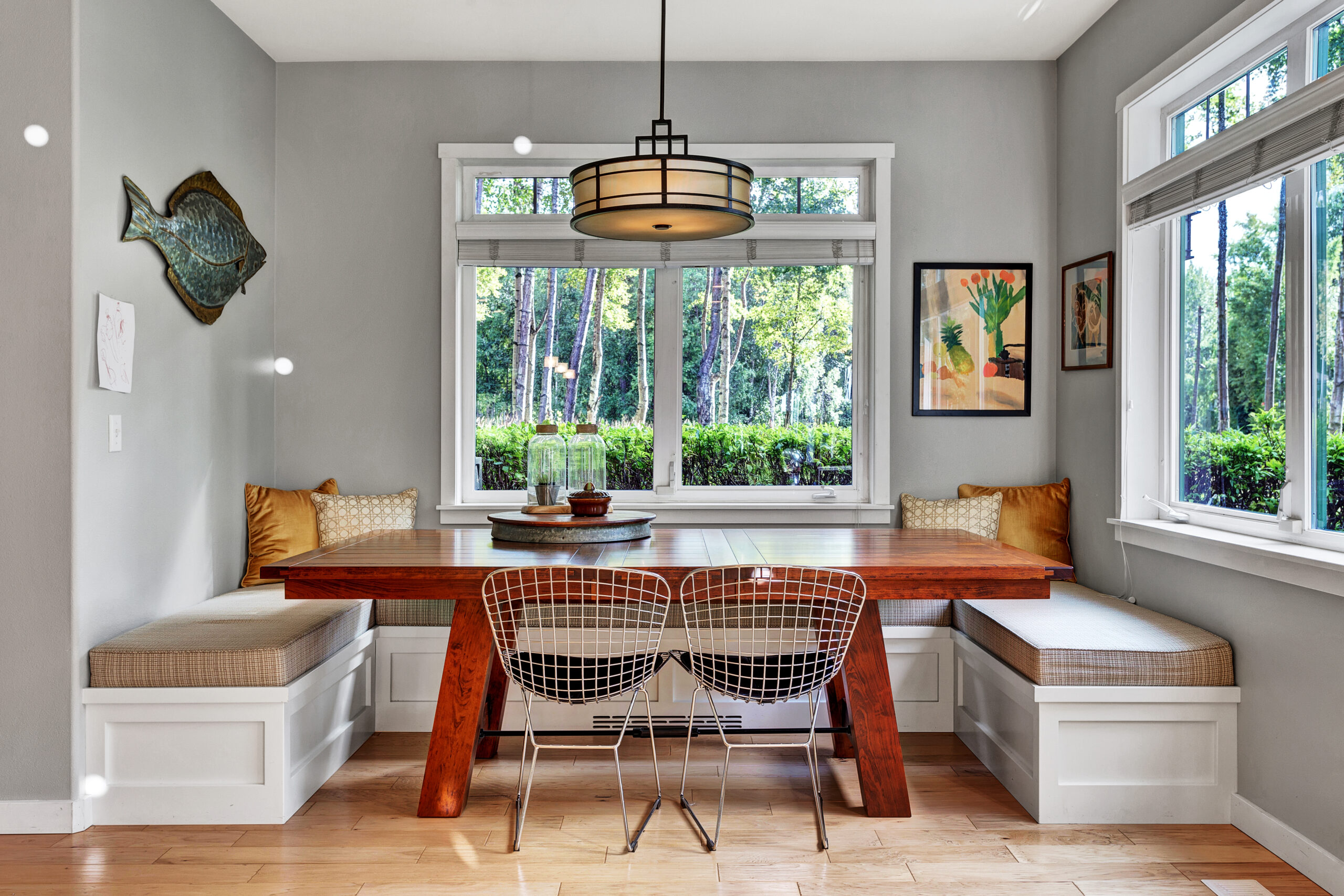 A contemporary kitchen nook and wooden dining table.  Banquette seating and large windows provide a cozy home corner for eating and socializing.  