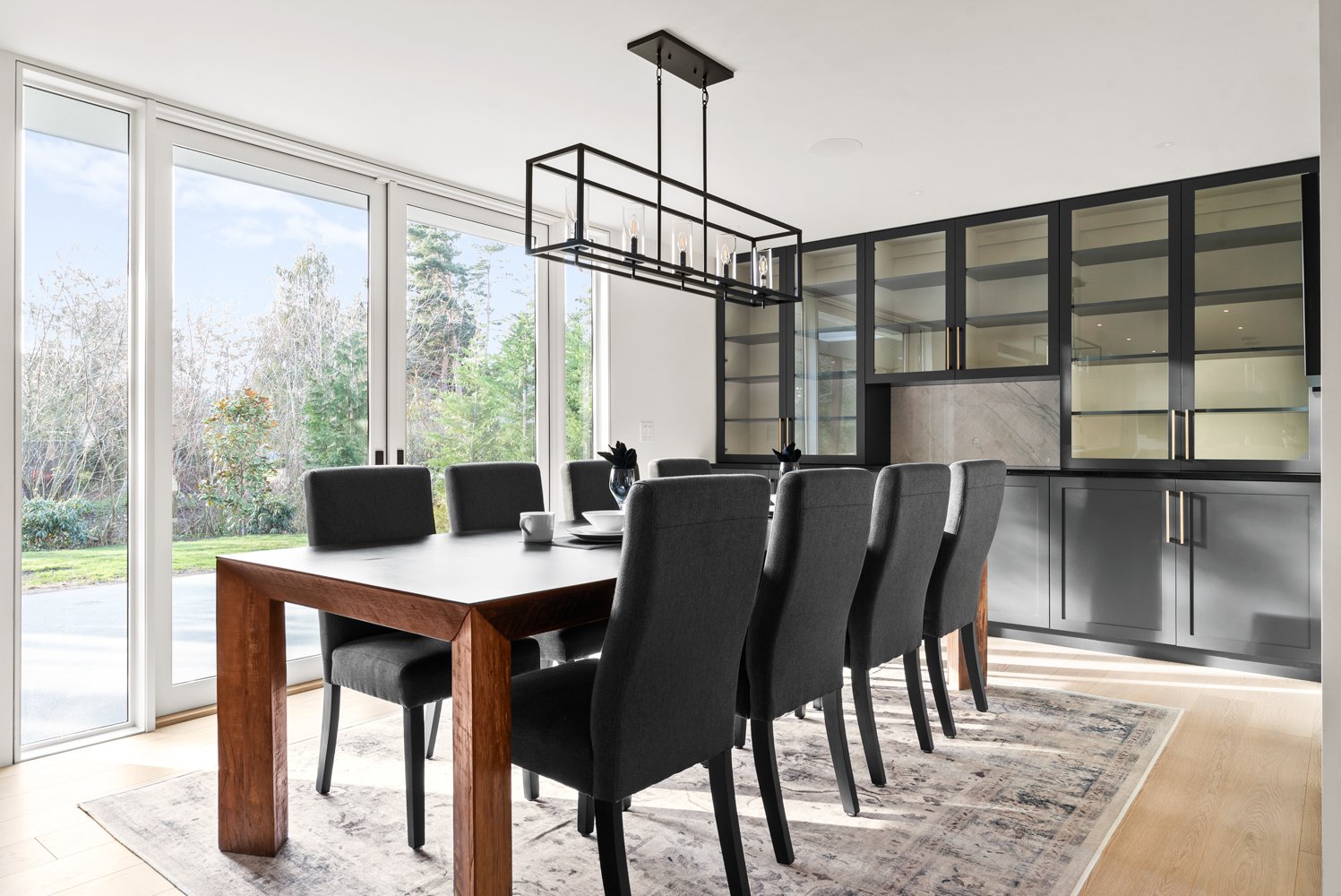 A beautifully staged dining room in Bellevue, WA, where elegance meets comfort. The warm glow of pendant lighting highlights the sleek table setting, inviting guests to gather for a memorable meal. Large windows frame a stunning view, adding to the ambiance of this sophisticated space.