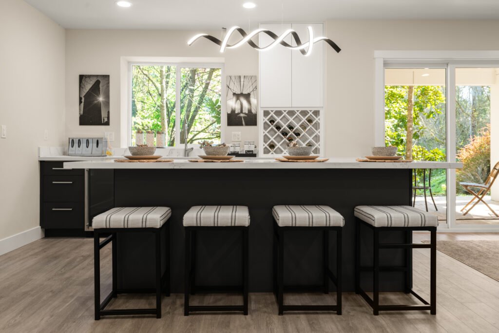 A modern kitchen featuring a spacious island with comfortable seating. The kitchen is illuminated by elegant contemporary lighting, enhancing the sleek design and sophisticated atmosphere.