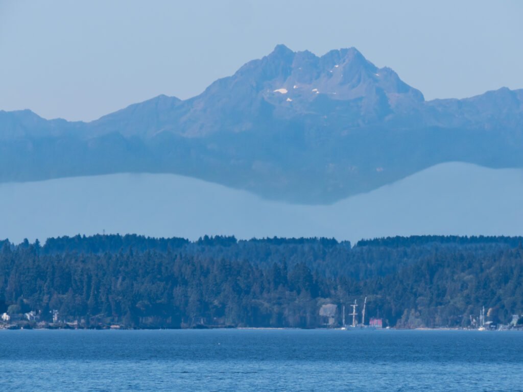 Olympic Mountains with layered ridgelines and snow-capped peaks across Puget Sound from West Seattle.