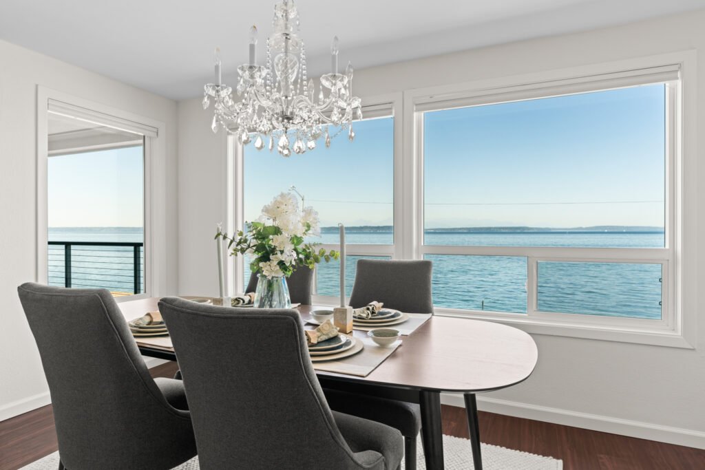 Modern dining area with Olympic Peninsula and Puget Sound views through white-framed windows.